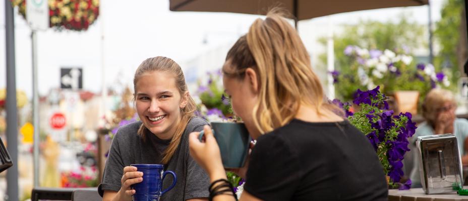 Patrons visiting at an outdoor cafe patio.