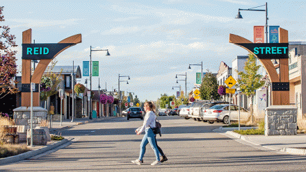 People walking across Reid Street by the gateway sign
